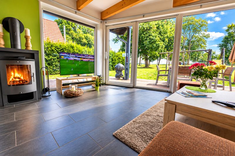 Wohnbereich von Benno mit Kaminofen, hellgrüner Wand und Blick auf Terrasse und Garten
